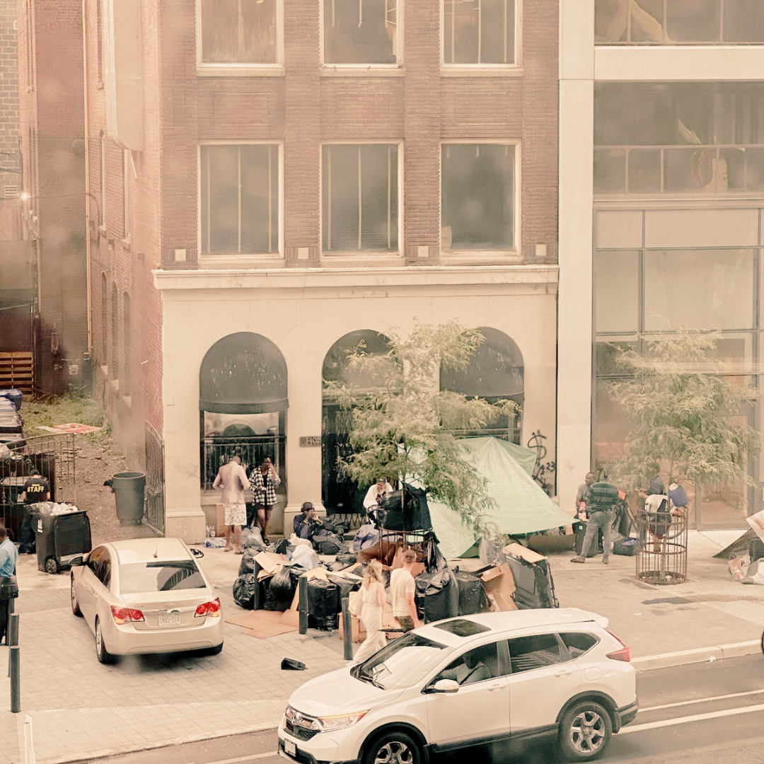 Migrant Crisis Toronto Image of migrants taking refuge on the sidewalk of a busy commercial street