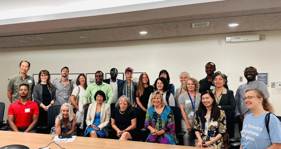 Refugee Serving Organizations, Frontline Service Workers, Health Organizations, and Civil Society Groups to Call for Urgent Action to Address Crisis Impacting Refugees in Toronto Image of board room with a team of diverse looking people